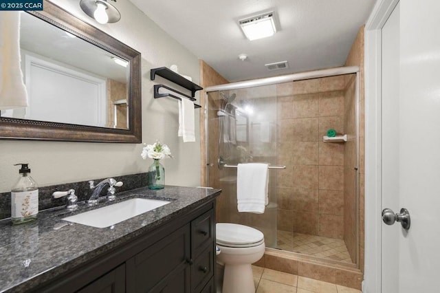 bathroom featuring toilet, tile patterned flooring, a shower with shower door, and vanity