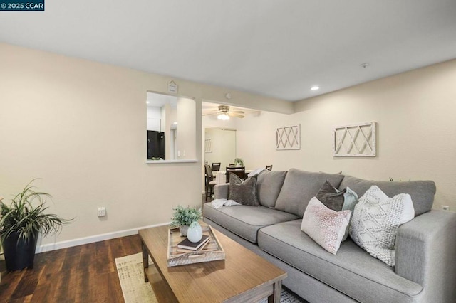 living room featuring ceiling fan and dark wood-type flooring