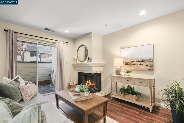 living room with a tile fireplace and hardwood / wood-style floors