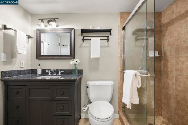 bathroom with a shower with shower door, toilet, and vanity