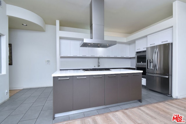 kitchen with white cabinets, stainless steel appliances, a kitchen island, and island range hood