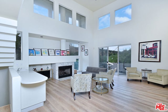 living room with light wood-type flooring, a high ceiling, and a fireplace