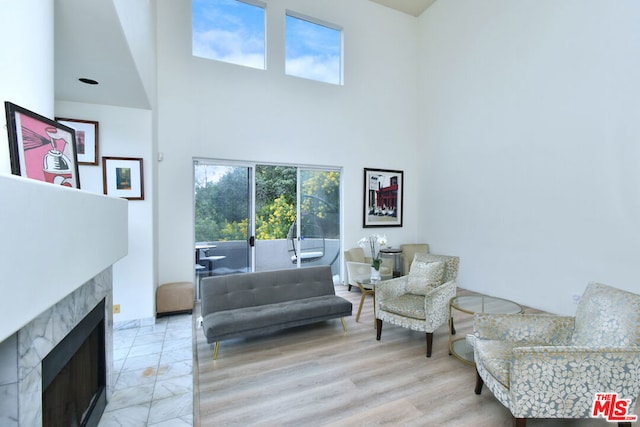 living room with a towering ceiling and a tile fireplace