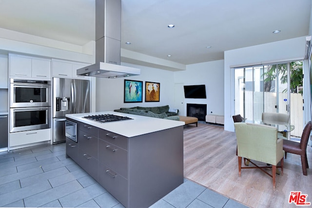 kitchen with a center island, appliances with stainless steel finishes, island exhaust hood, white cabinets, and gray cabinets