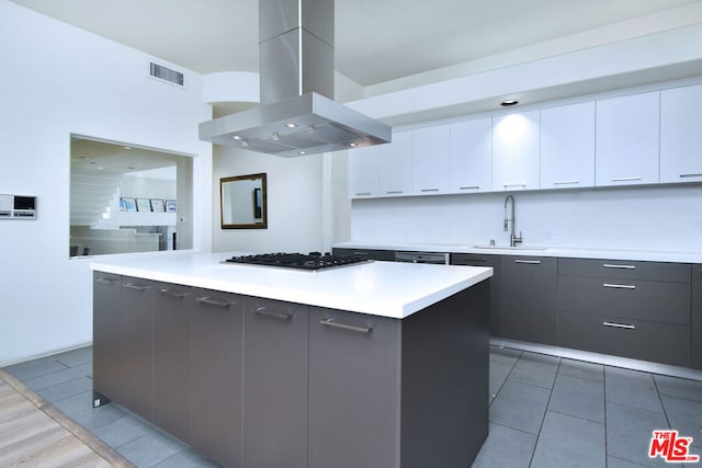 kitchen with a center island, white cabinetry, island exhaust hood, and sink