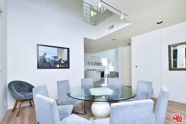 dining area with a fireplace, light wood-type flooring, and track lighting