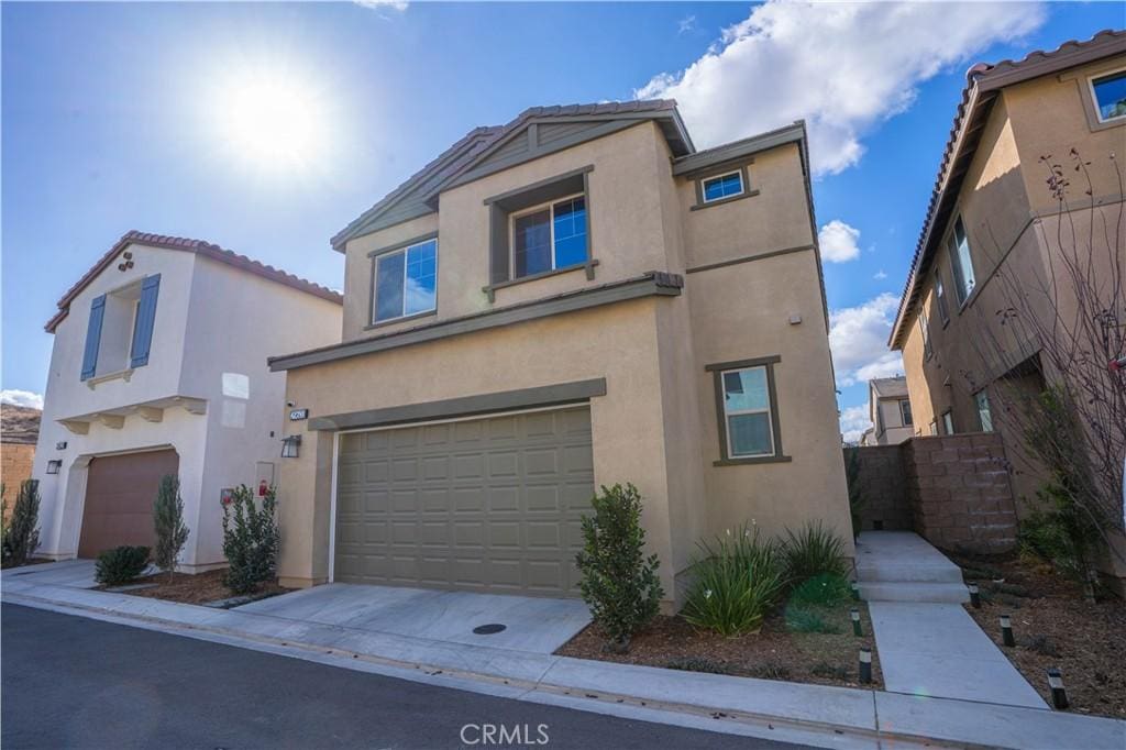 view of front of property featuring an attached garage, concrete driveway, and stucco siding