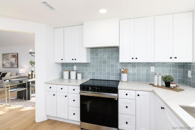 kitchen with white cabinets, light wood-type flooring, and electric range oven