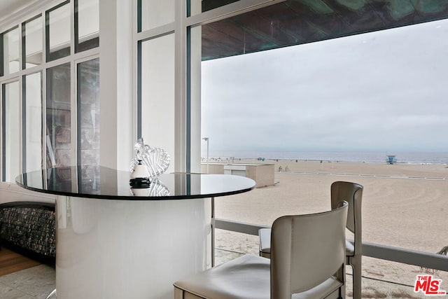 interior space with a water view, a view of the beach, and light tile patterned floors