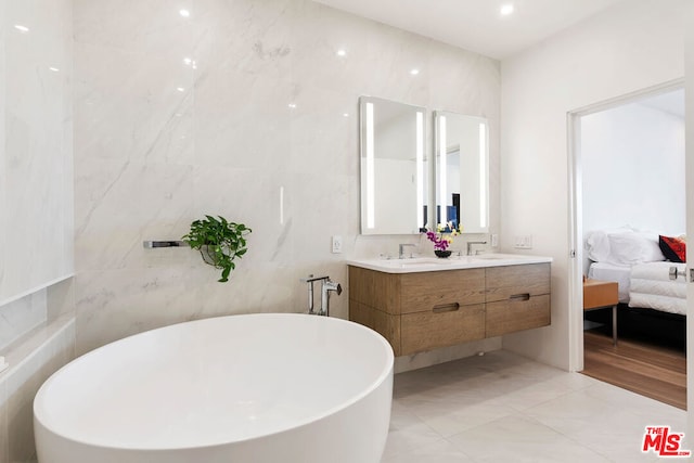 bathroom with tile walls, a bathtub, and vanity