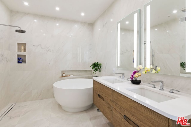 bathroom with vanity, shower with separate bathtub, and tile walls