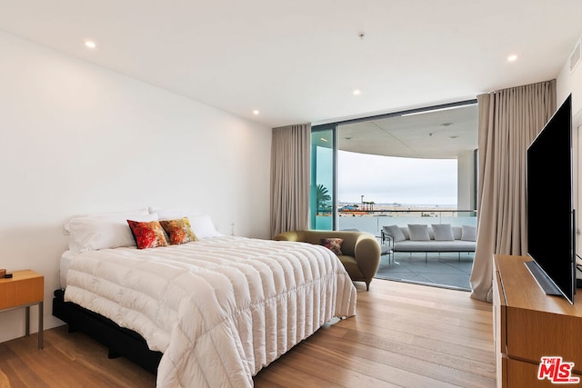 bedroom with light hardwood / wood-style floors and a wall of windows