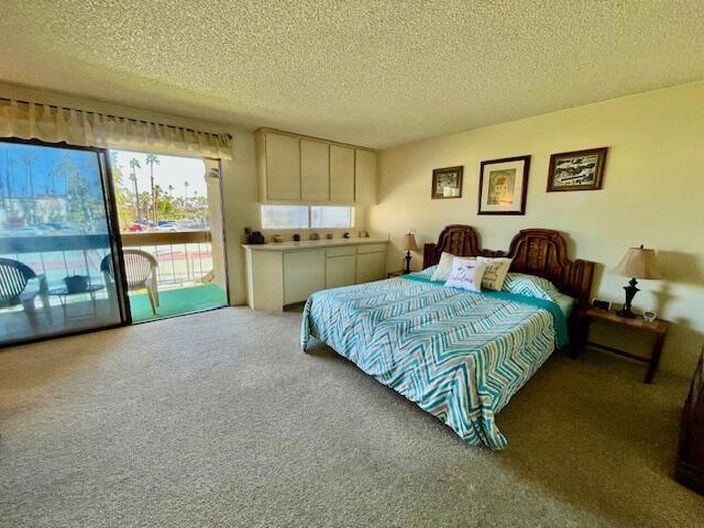 bedroom featuring carpet floors, a textured ceiling, and access to outside