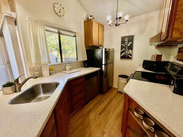 kitchen featuring light hardwood / wood-style flooring, decorative light fixtures, sink, a textured ceiling, and stainless steel appliances