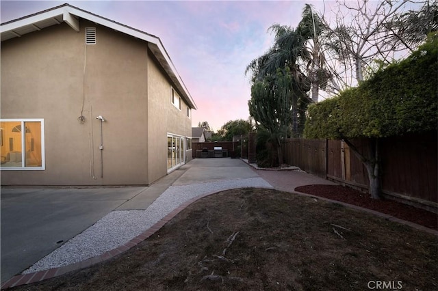 property exterior at dusk with a patio