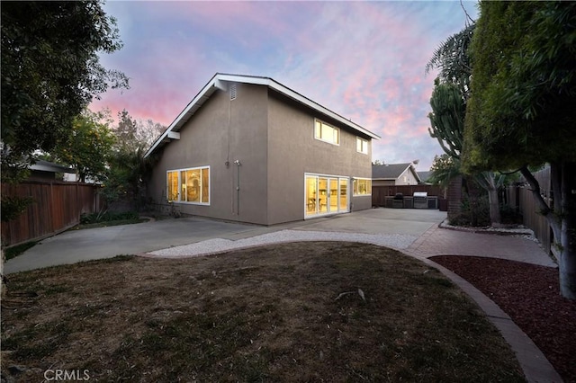 back house at dusk with a patio area