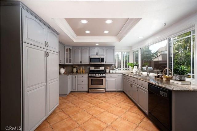 kitchen with sink, appliances with stainless steel finishes, gray cabinetry, tasteful backsplash, and a raised ceiling