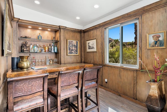 bar with wood walls, light hardwood / wood-style flooring, and butcher block counters