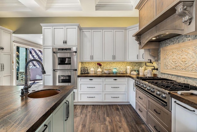 kitchen with premium range hood, white cabinets, and appliances with stainless steel finishes