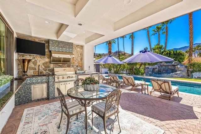 view of patio with a grill, an outdoor kitchen, sink, a fenced in pool, and a mountain view