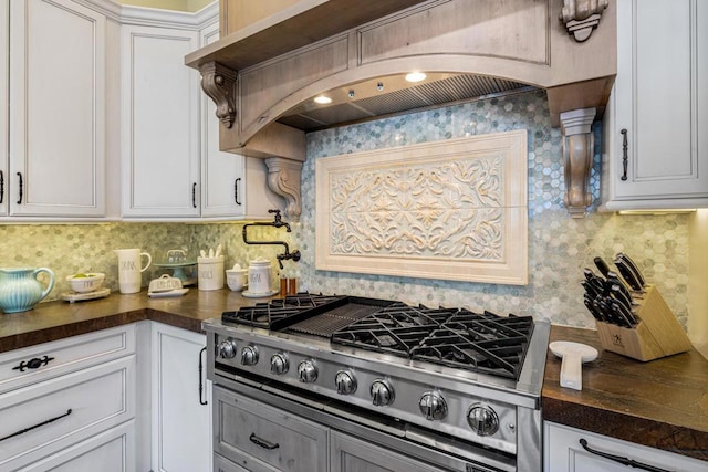 kitchen with white cabinetry, dark stone countertops, tasteful backsplash, premium range hood, and stainless steel gas cooktop