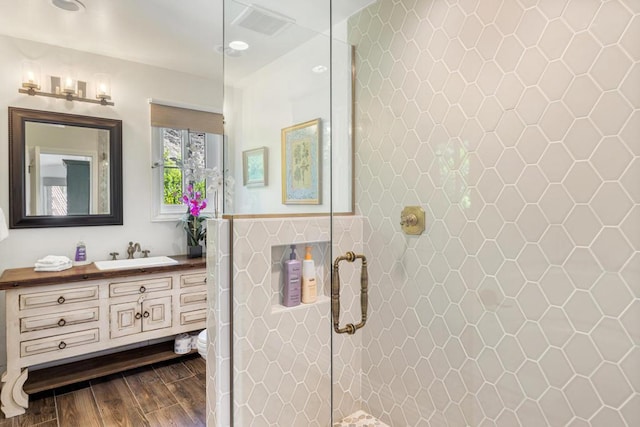 bathroom with a tile shower, hardwood / wood-style floors, toilet, and vanity