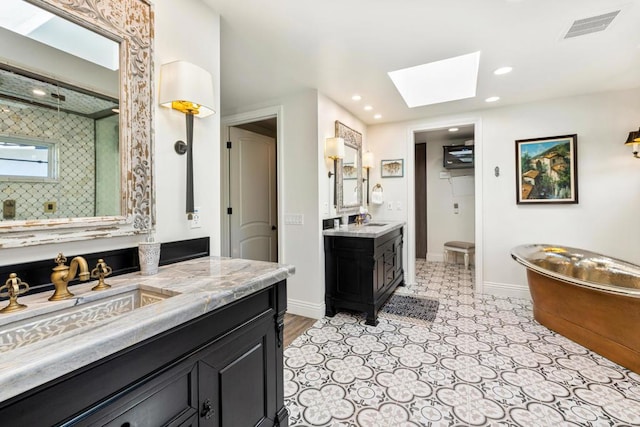 bathroom with a tub to relax in, vanity, and a skylight