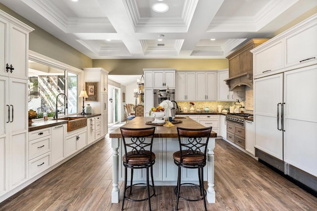 kitchen with beamed ceiling, coffered ceiling, white cabinetry, custom range hood, and decorative backsplash