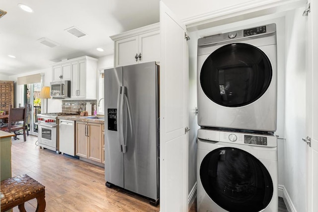 washroom featuring light hardwood / wood-style floors, stacked washer / dryer, and sink