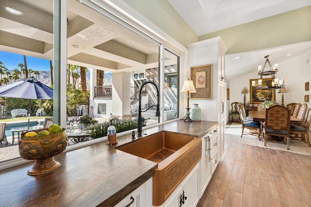 kitchen featuring sink, white cabinets, a chandelier, and light wood-type flooring