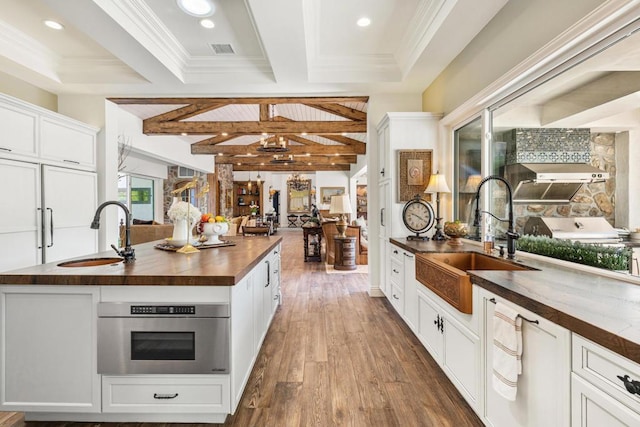 kitchen featuring sink, white cabinets, beam ceiling, and wooden counters