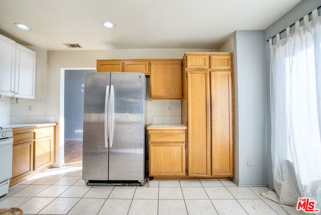 kitchen with light tile patterned floors, stainless steel fridge, and stove