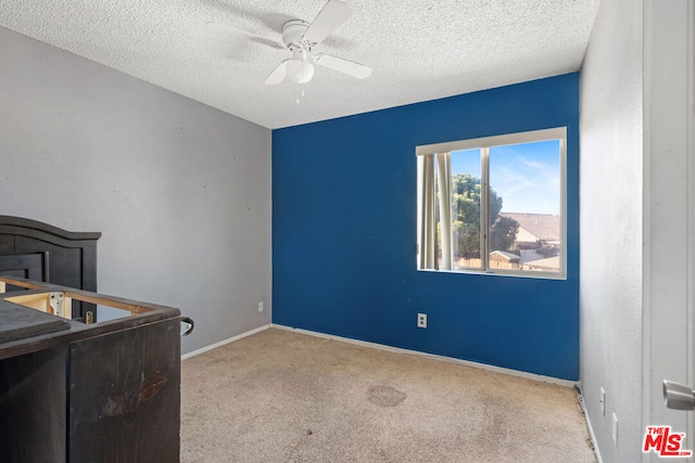 bedroom featuring ceiling fan, a textured ceiling, and light carpet