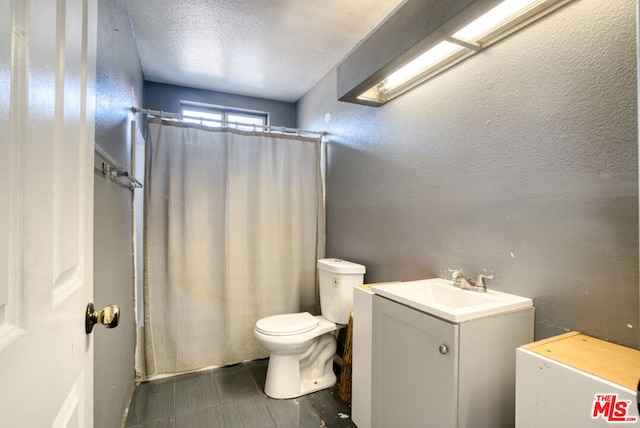 bathroom with toilet, a textured ceiling, a shower with shower curtain, and vanity