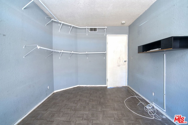 spacious closet featuring dark parquet flooring