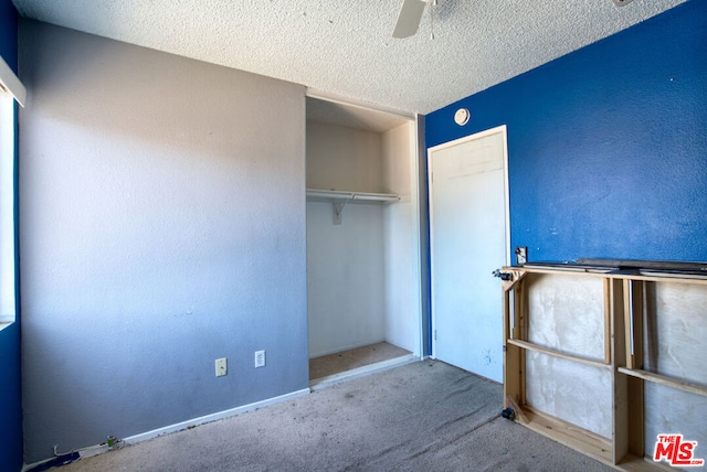 unfurnished bedroom with ceiling fan, a textured ceiling, a closet, and carpet floors