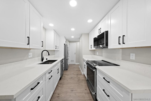 kitchen featuring sink, white cabinets, light hardwood / wood-style flooring, and stainless steel appliances