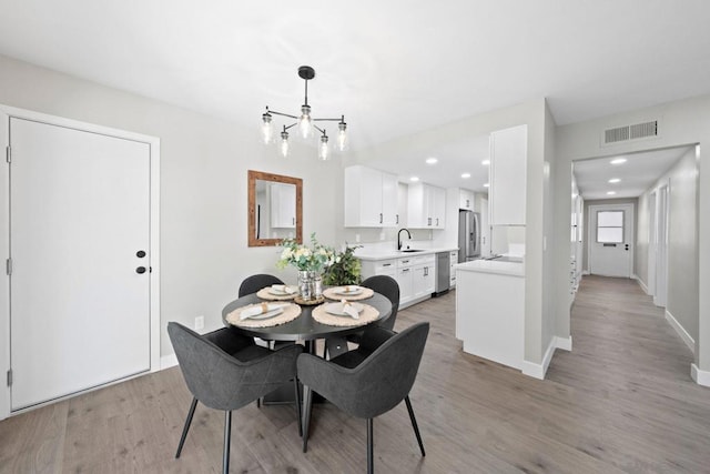 dining room featuring sink, a chandelier, and light hardwood / wood-style floors