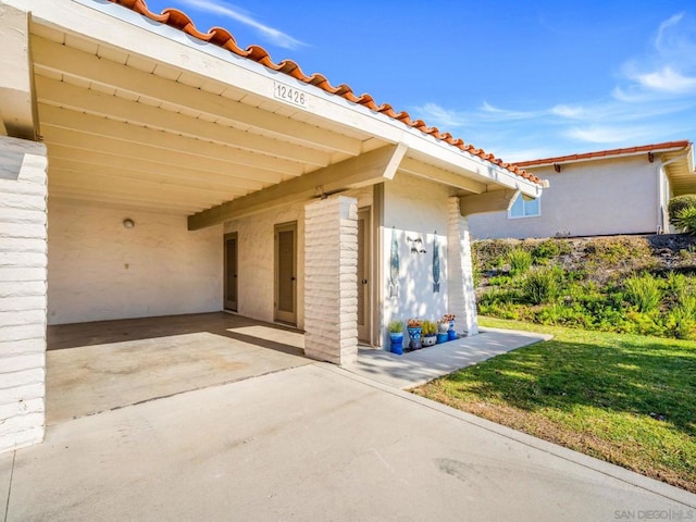 property entrance featuring a lawn and a carport