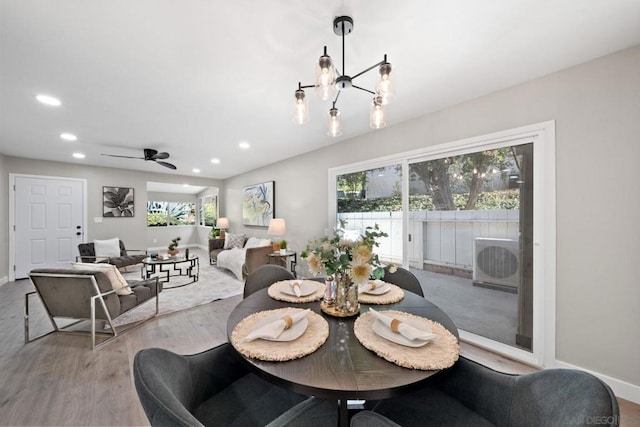 dining room with ceiling fan with notable chandelier, a healthy amount of sunlight, and light hardwood / wood-style flooring