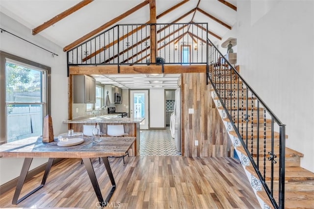 dining room with beamed ceiling, high vaulted ceiling, and light hardwood / wood-style floors