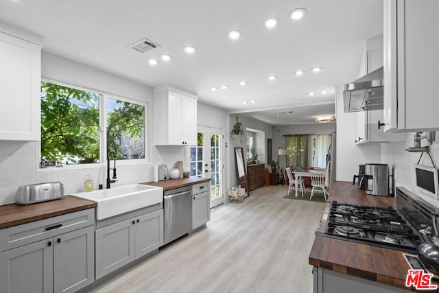 kitchen with sink, light hardwood / wood-style flooring, dishwasher, and wooden counters