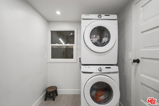 laundry area with light hardwood / wood-style floors and stacked washer / drying machine