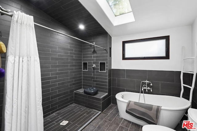 bathroom featuring vaulted ceiling with skylight, tile walls, and plus walk in shower