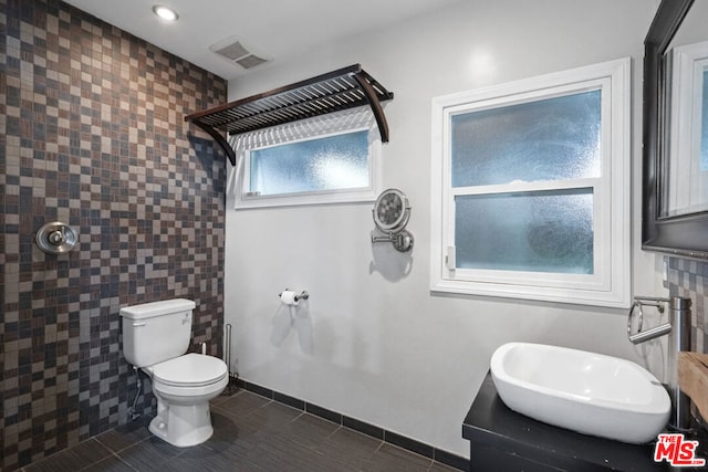 bathroom featuring toilet, tile patterned flooring, walk in shower, and vanity