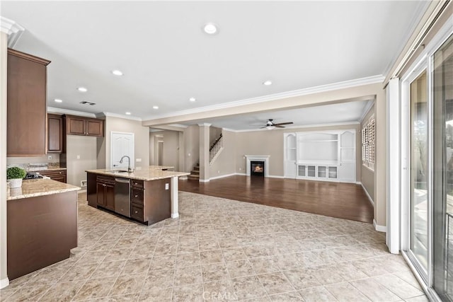 kitchen featuring sink, light stone counters, a center island with sink, dishwasher, and ceiling fan