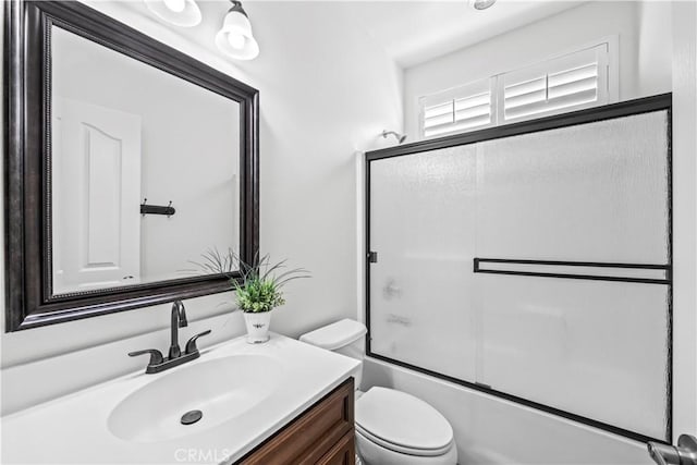 full bathroom with enclosed tub / shower combo, vanity, and toilet