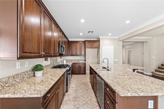 kitchen with sink, light stone counters, crown molding, a center island with sink, and stainless steel appliances