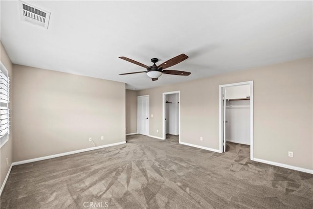 unfurnished bedroom with ceiling fan, a spacious closet, a closet, and carpet flooring