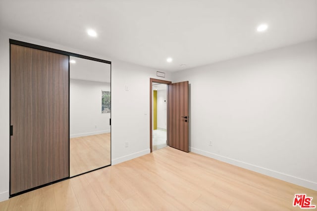 unfurnished bedroom featuring light wood-type flooring and a closet